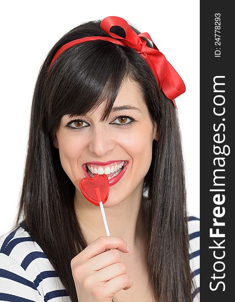 Young retro girl biting a red heart shape lollipop. she is brunete, and is smiling wears a red bow in her hair. Young retro girl biting a red heart shape lollipop. she is brunete, and is smiling wears a red bow in her hair.