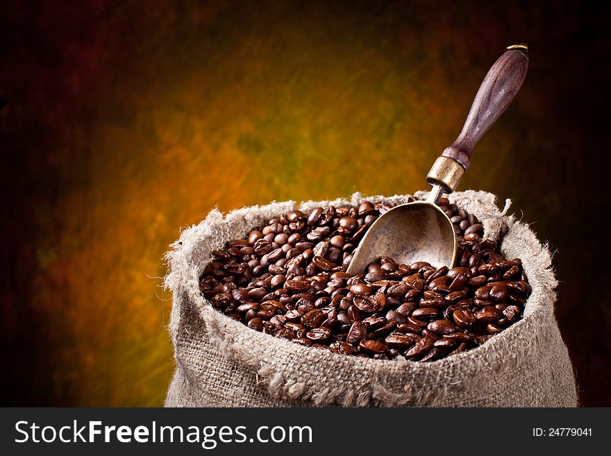 Sack of coffee beans and scoop. On a dark background.