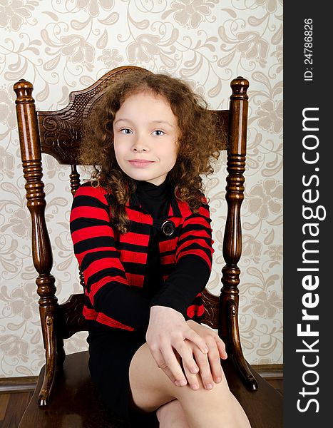 Portrait of ctue little girl sitting on a chair