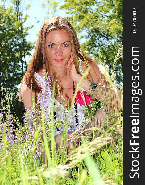 Beautiful young woman between flowers in the nature