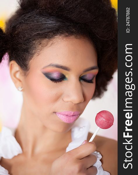 Beautiful afro-american woman holding lollipop on colorful background. Beautiful afro-american woman holding lollipop on colorful background