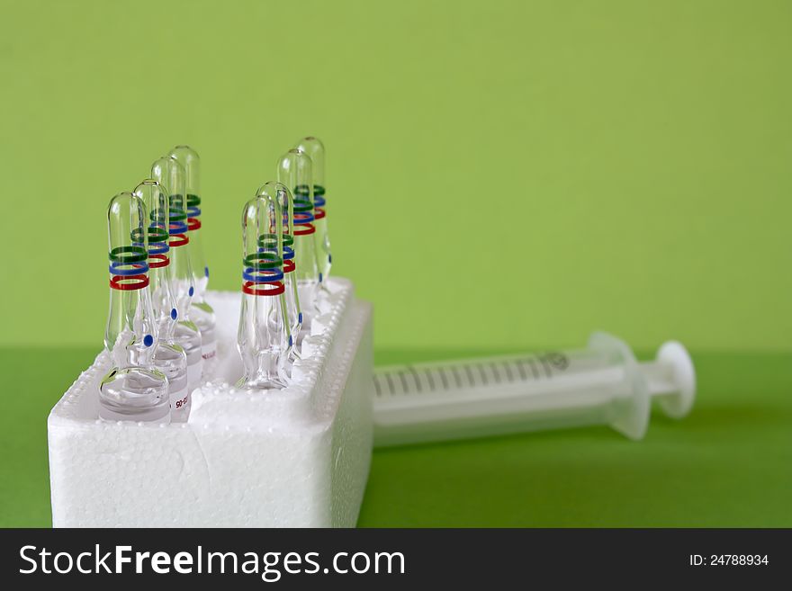 Closeup view of  medical vitamin ampules for syringes on green background. Closeup view of  medical vitamin ampules for syringes on green background.
