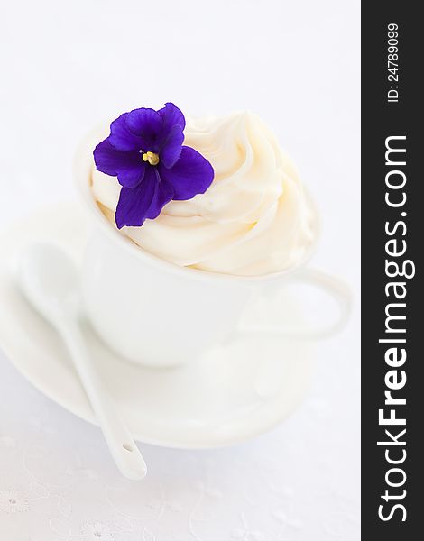 White chocolate mousse decorated with violet flowers, selective focus