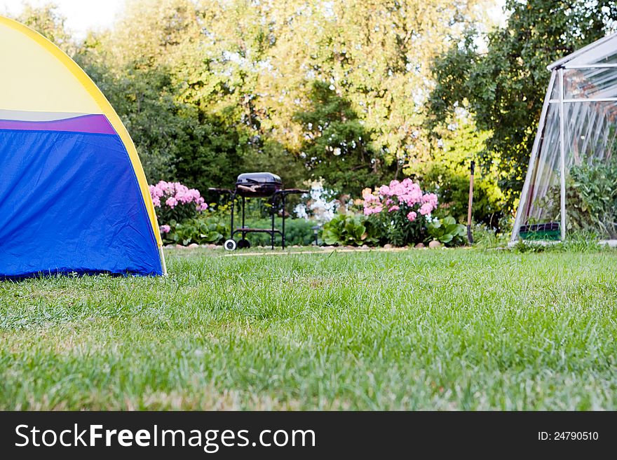 Enjoying adventure and nature during a summer vacation spent camping out at a pretty campsite with trees and a barbecue. Enjoying adventure and nature during a summer vacation spent camping out at a pretty campsite with trees and a barbecue