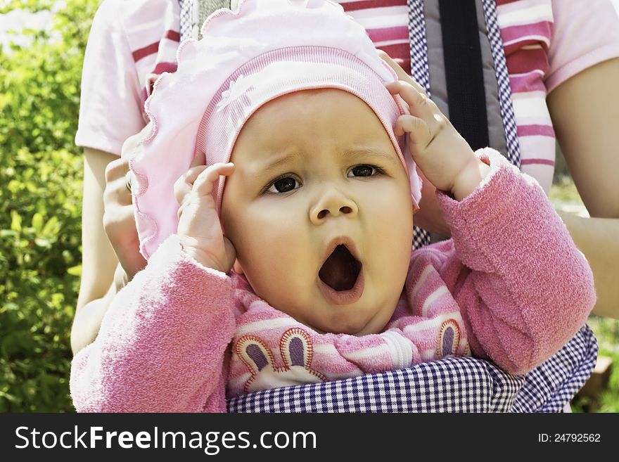 Closeup portrait of yawning baby girl in a pink jacket on the street. Closeup portrait of yawning baby girl in a pink jacket on the street