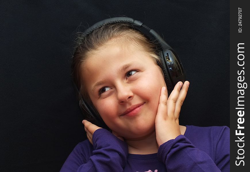 Little girl is listening music with headphone
