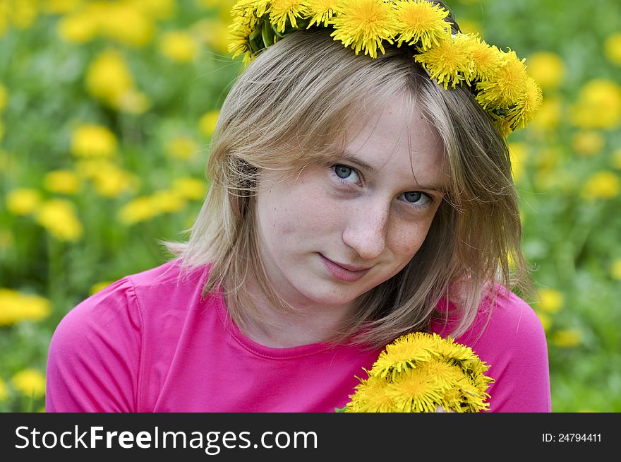 Happy girl in a wreath from yellow dandelions admires flowers. Happy girl in a wreath from yellow dandelions admires flowers