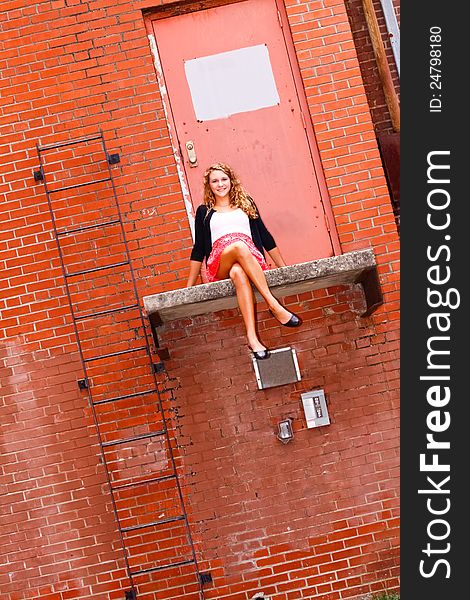 Pretty Teenage Girl Sitting on a Ledge