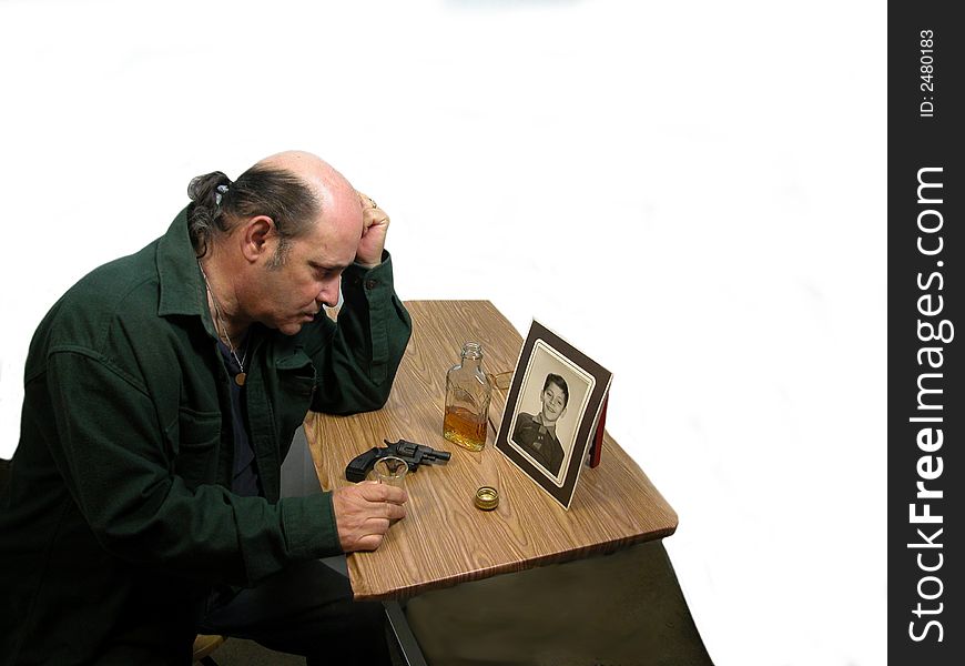 A man in deep dispair, looking at a photo, sad and in thought... whiskey and gun on a table. .