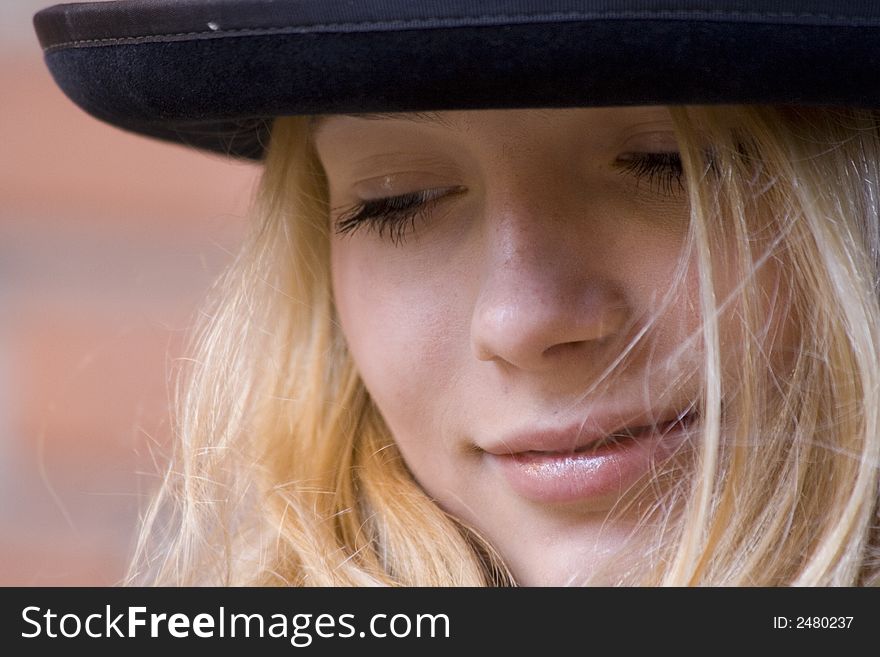 Portrait of the beautiful girl in a hat on a background of an old brick wall. Portrait of the beautiful girl in a hat on a background of an old brick wall