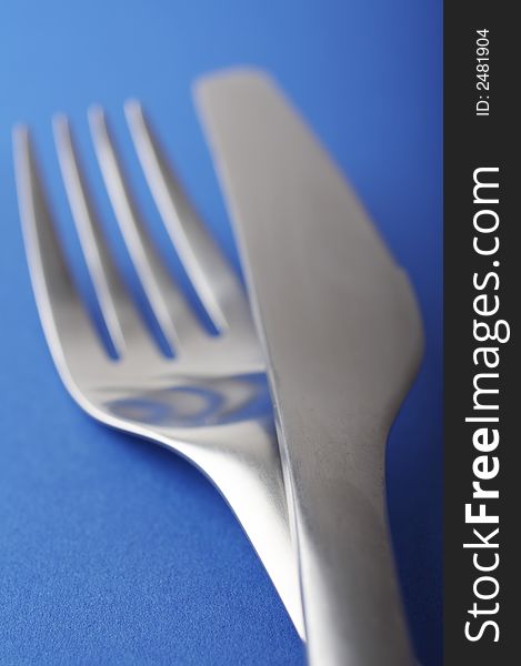 Close up of a fork and spoon on blue background, shallow DOF. Close up of a fork and spoon on blue background, shallow DOF