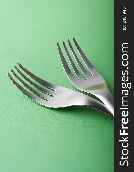 Two forks head on green paper background, shallow DOF
