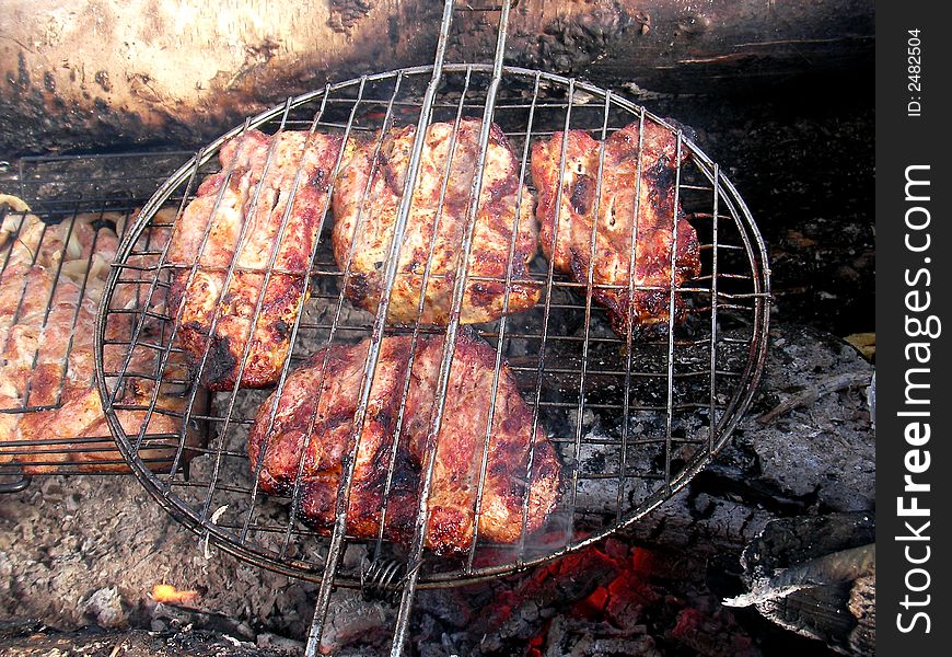 Slices of a pork on the grillwork above glowing embers. Slices of a pork on the grillwork above glowing embers