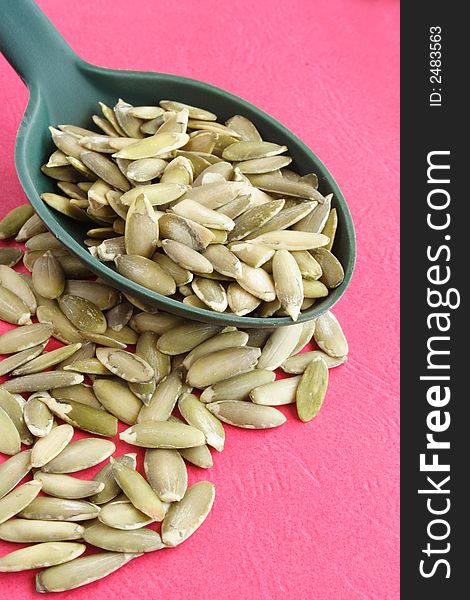 Pumpkin seeds on a green spoon and table