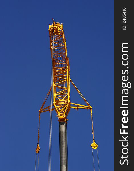 Head of a big yellow crane on a blue sky background. Head of a big yellow crane on a blue sky background