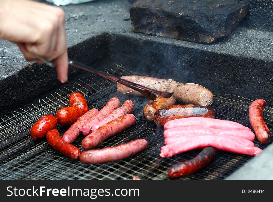 Cooking white and red sausage on outdoor barbecue