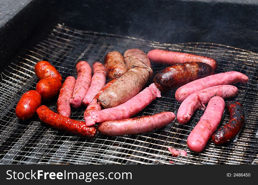 Cooking white and red sausage on outdoor barbecue