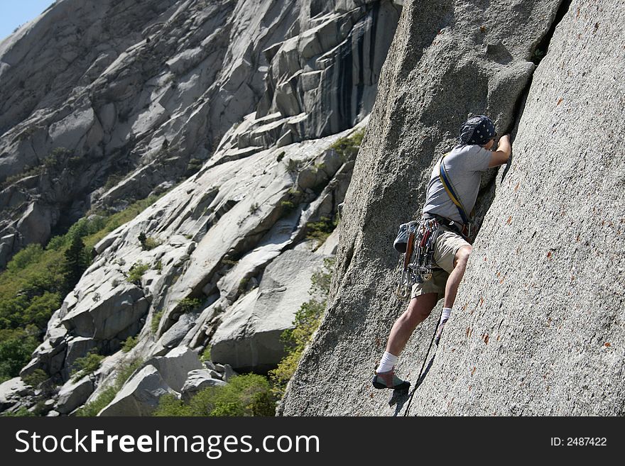 A man placing gear on a rock climb. A man placing gear on a rock climb