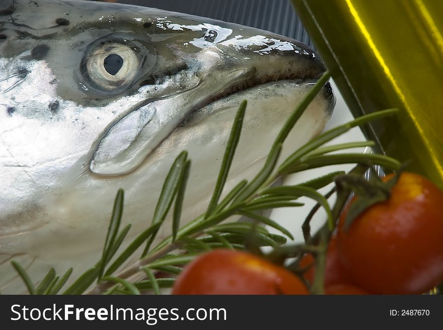 Salmon fish head close up with rosemary oil and tomato in background