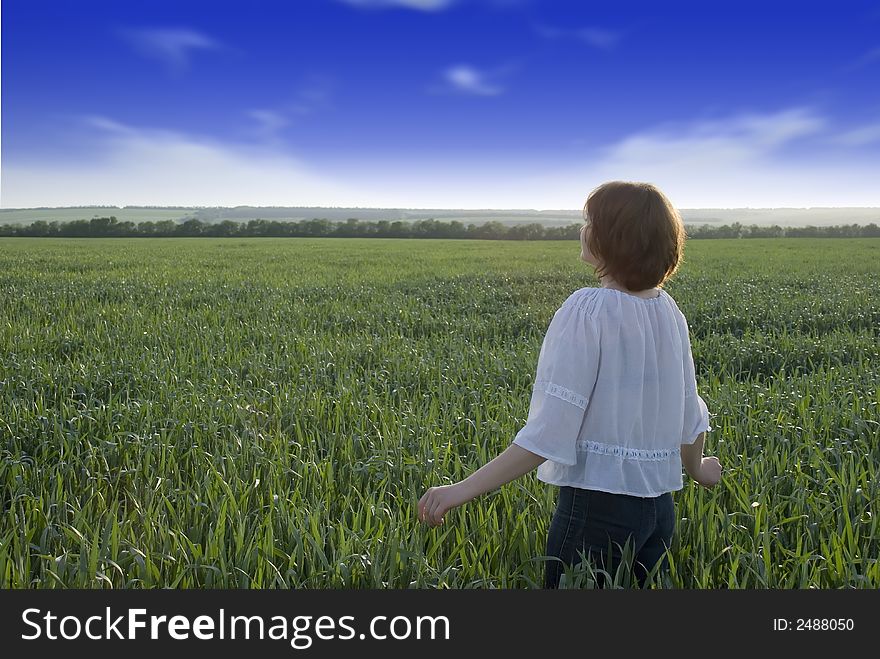 The girl on a meadow. A field of wheat, the contrast sky and the girl looking in a distance