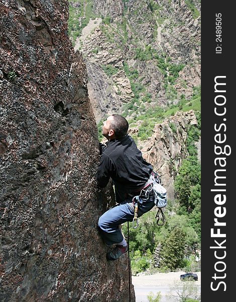 A rock climbing man climbs the edge of an arete. A rock climbing man climbs the edge of an arete