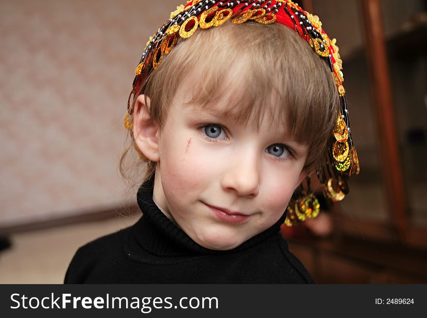 Girl in embroidered skull-cap poses at home
