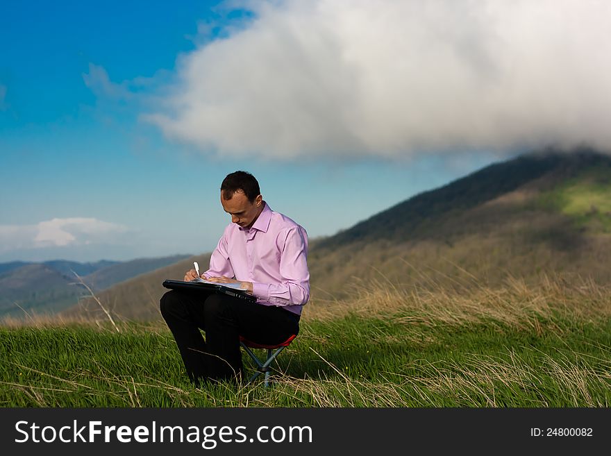 Man writes in paper sitting on mountain. Man writes in paper sitting on mountain