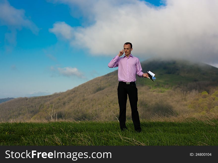 Man speaks on telephone and takes notepad staying on mountain. Man speaks on telephone and takes notepad staying on mountain