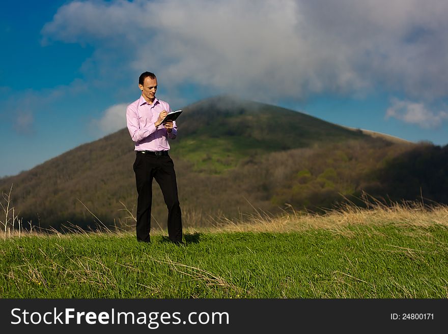 Man writes in notepad sitting on mountain. Man writes in notepad sitting on mountain