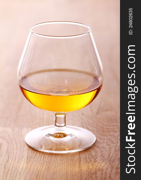 Glass Of Cognac Over Wooden Surface