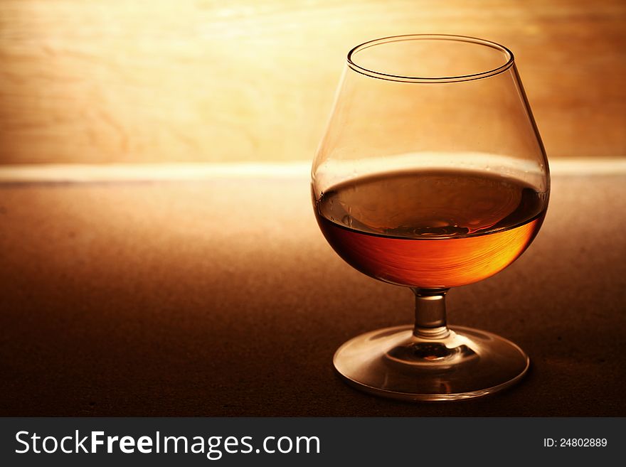 Glass of hot cognac over wooden surface