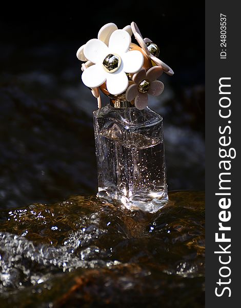 A bottle of parfum on a rock in the water. A bottle of parfum on a rock in the water