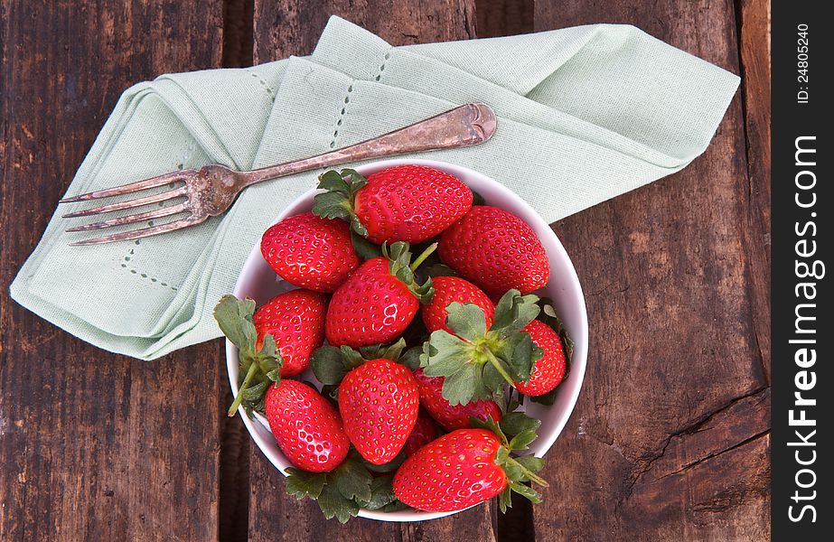 Strawberries on wooden background with vintage fork and napkin