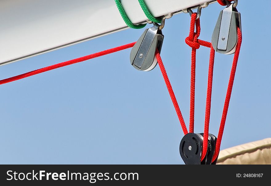 Sailing rigging. Blocks and red cords. Detail of yacht. Ropes of sailboat - tackles on the rigging yacht. Yachting equipping - pulleys blocks.