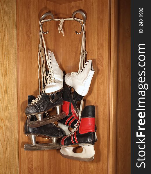 Three pairs of old skates hanging in the closet