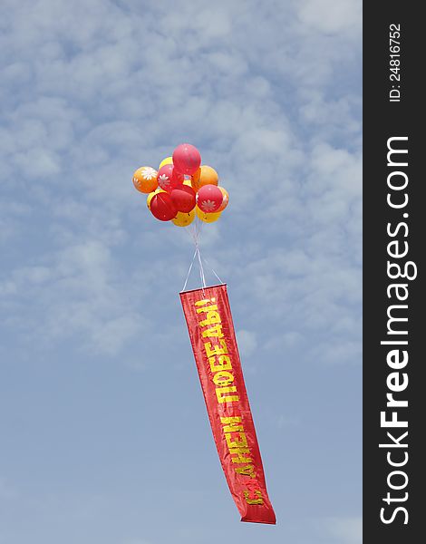 Multi-colored balloons with a banner against the blue sky with clouds. Multi-colored balloons with a banner against the blue sky with clouds