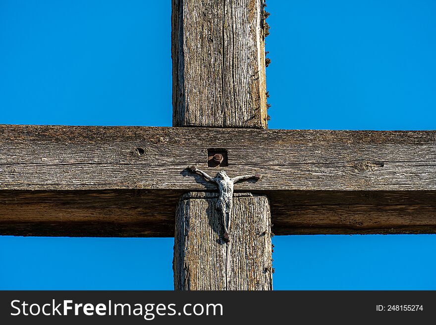 An old wooden cross against a clear blue sky. The crucified Jesus on the cross. The concept of the pure and unrequited love of God
