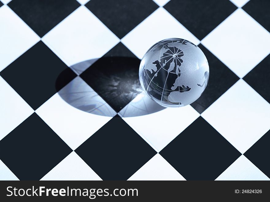 Chess concept. Transparent glass globe lying on chessboard. Chess concept. Transparent glass globe lying on chessboard