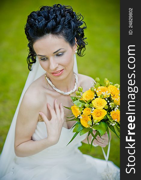 Portrait of beautiful young bride in garden .Play with bouquet