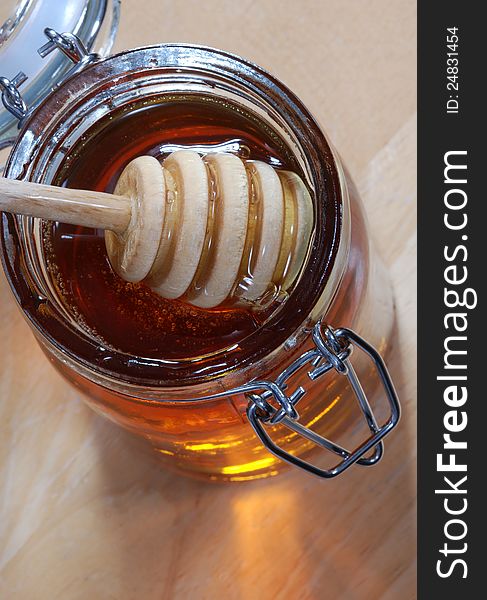 A jar of honey with stir stick, natural outdoor background