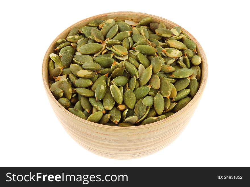 A bowl of Roasted and Salted Pumpkin seeds, isolated on white background