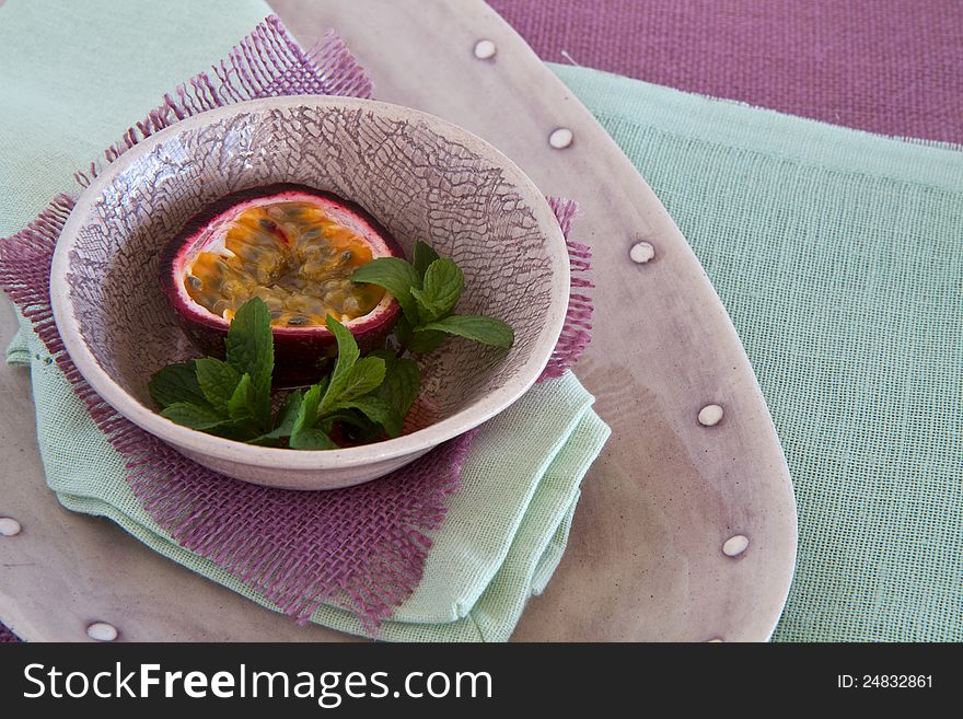 Bowl of granadilla and mint on colorful linen. Bowl of granadilla and mint on colorful linen
