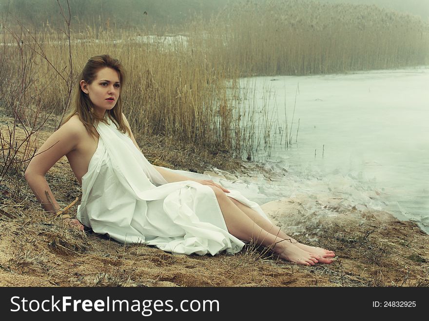 Woman in white dress in the winter on the rushy lake