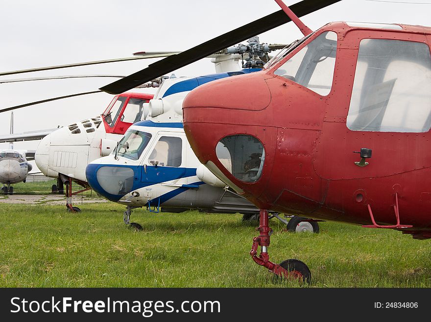 Old helicopters on airfield against green grass background