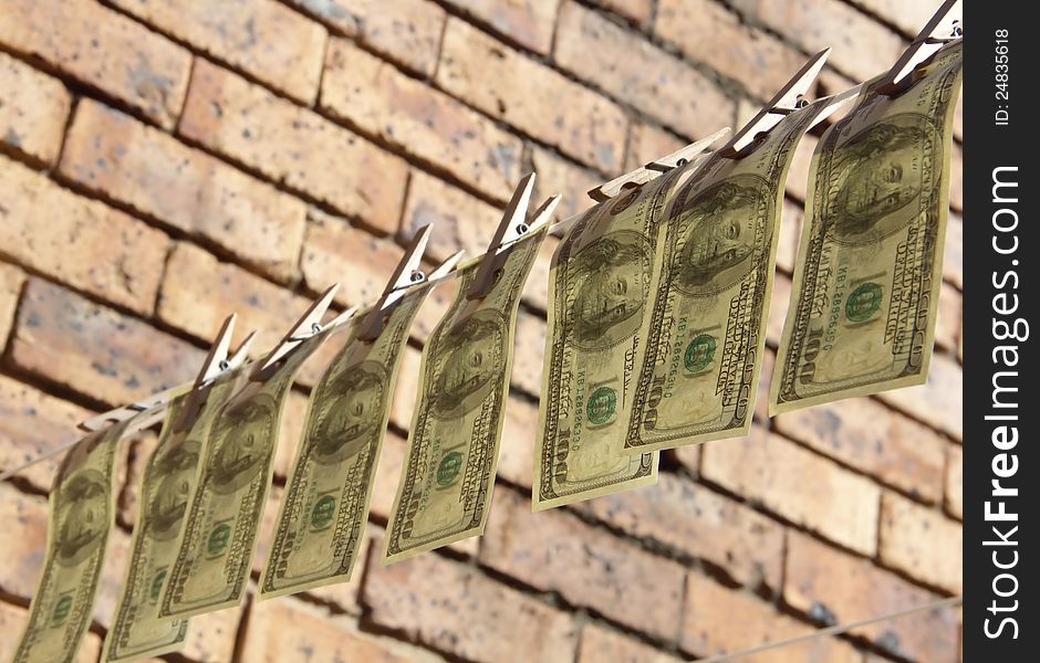 One hundred dollar bills is hanging on rope on bricks background. One hundred dollar bills is hanging on rope on bricks background