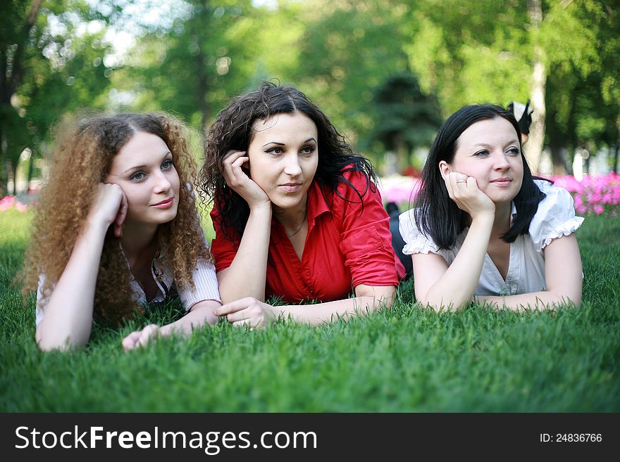 Portrait of three friends on the grass in the park