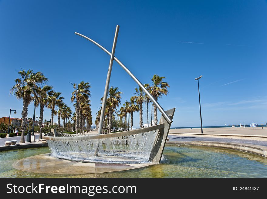 The boat-like fountain under the blue sky on the beach in Valencia. The boat-like fountain under the blue sky on the beach in Valencia.