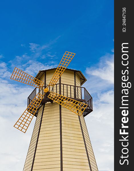 Windmill with yellow vane in blue sky background. Windmill with yellow vane in blue sky background
