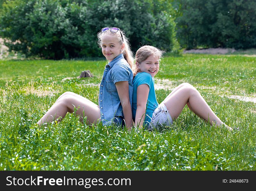 Two cheerful girls sitting on grass. Two cheerful girls sitting on grass