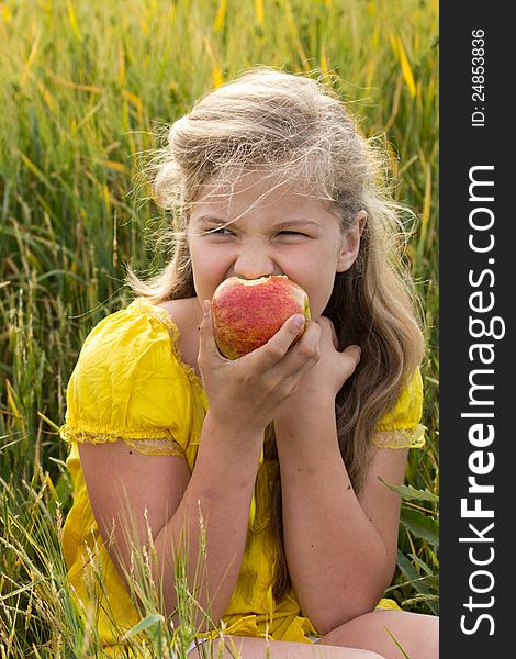 Portrait of a young beautiful girl with red apple at the wheat field. Portrait of a young beautiful girl with red apple at the wheat field